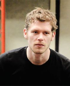 a man in black shirt holding a cell phone to his ear and looking at the camera