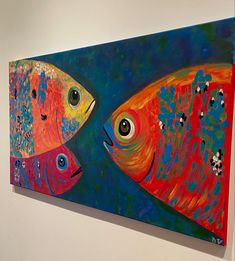 two colorful fish on a white wall next to each other