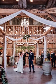 a bride and groom dancing at their wedding reception in front of an open barn door