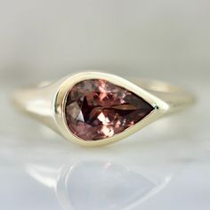 a gold ring with a large pink stone in the center and a thin band around it