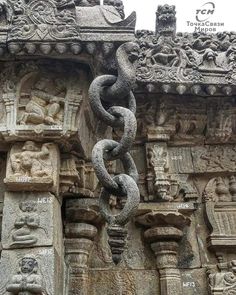 a large chain hanging from the side of a stone building with carvings on it's sides