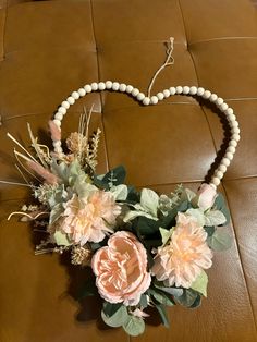 a heart shaped necklace with flowers and beads on a brown leather couch in a living room