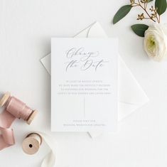 the wedding stationery is laid out on top of some white paper and pink ribbon