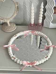 a mirror and some candles are on a table with pink ribbons around the edges, along with other decorative items