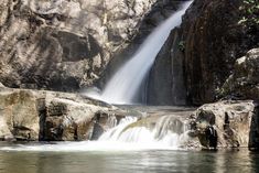 there is a waterfall in the middle of some rocks and water flowing down it's sides