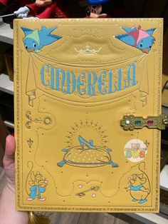 someone is holding up a book with the word cinderella written in blue and gold on it