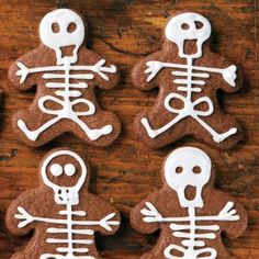 four decorated cookies with white icing in the shape of skeletons