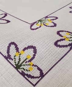 a cross stitch table runner with flowers and hearts on the border, in purple and white