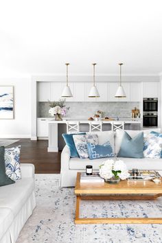 a living room filled with white furniture and lots of blue pillows on top of it