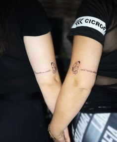 two people holding hands with tattoos on their arms