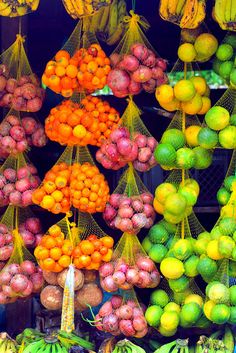 various fruits and vegetables on display in a market stall with mesh bags hanging from the ceiling