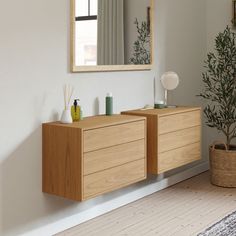 a bathroom with a mirror, sink and wooden cabinet in the corner next to a potted plant