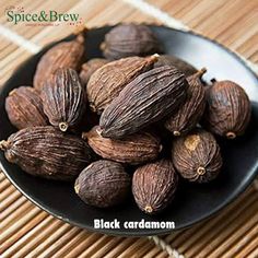 black cardamon seeds in a bowl on a bamboo mat