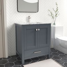 a white toilet sitting next to a gray sink in a bathroom under a framed mirror