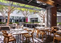 an empty restaurant with tables and chairs in front of large windows that overlook the courtyard