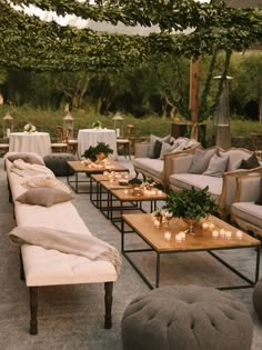 an outdoor seating area with couches, tables and candles on the tables in front of them