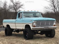 an old blue and white truck parked in a field