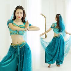 a woman in a blue belly dance outfit and headpiece is standing with her arms outstretched