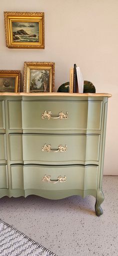 a green dresser with pictures on top of it and a rug in front of it