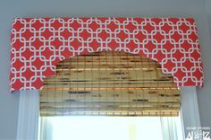 an orange and white window valance hanging over a window with bamboo blinds on it