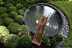 an aerial view of a garden pond surrounded by trees and bushes with lights on the side