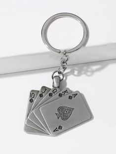 four playing cards are hanging from a metal keychain on a white surface,