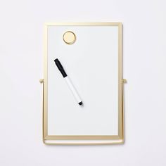 a white board with a black pen on it next to a gold framed piece of paper