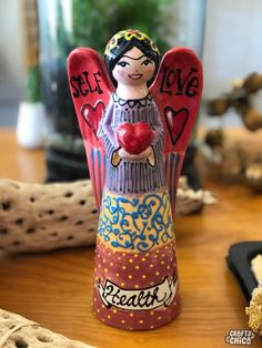 an angel figurine holding a heart on top of a wooden table next to other items