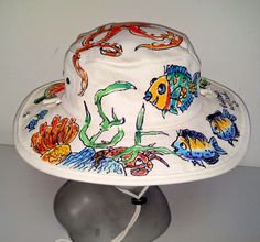 This is a great hat for the outdoors! Whether you're into gardening, fishing, or walking on the beach, this hat will shield you from that summer sun. Adjustable chin cord will keep it from blowing away on a windy day. 100% heavy cotton canvas, natural color; individually hand painted all over all kinds of fish, starfish, crab, corals and an octopus on top.... Send convo message if you have any custom requests. Each hat is painted freehand, so no two look exactly alike. The acrylic paints used are permanent, so if your hat happens to land in the water, not to worry. The hat might be all wet, but the painted design will still be there. One size, fits L-XL. Hand wash. If you need something smaller, send me a message. I'll recommend another style for you. Sharpie Projects, Rocker Tank, Reef Fish, Outback Hat, Winston Salem Nc, Painted Hats, Truck Shirts, Painted Jeans, Hat For Men