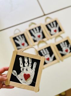 a person holding up a handprinted picture with hearts on it and six other pictures in the background