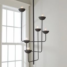 a black chandelier with five lights hanging from it's sides in front of a window