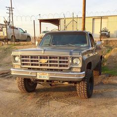 the truck is parked on the side of the road in front of a barbed wire fence