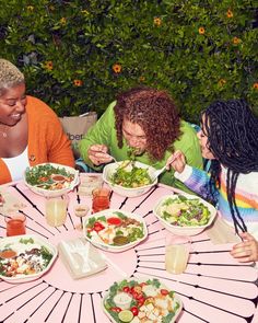 four women sitting around a table eating salad