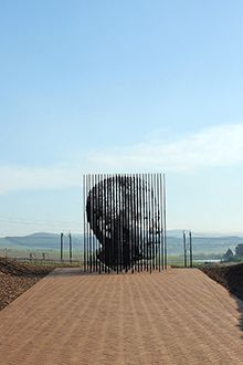 a large metal sculpture sitting on top of a dirt road