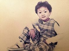 a young boy sitting on the floor with his feet up and wearing plaid pants,