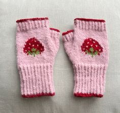 two pink knitted gloves with red flowers on them