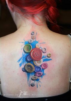 the back of a woman's neck with buttons painted on her upper and shoulder