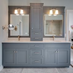 a large bathroom with two sinks and gray cabinets