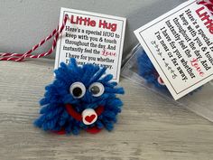 a blue stuffed animal sitting on top of a wooden table next to a tag that says, little hug here's a special gift for us to keep with your touch throughout the