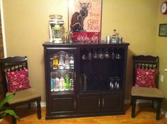 there is a liquor cabinet in the corner of this room with two chairs next to it