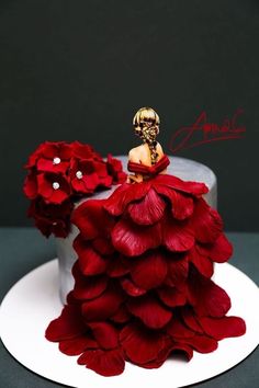 a cake decorated with red flowers and a woman's head sitting on top of it