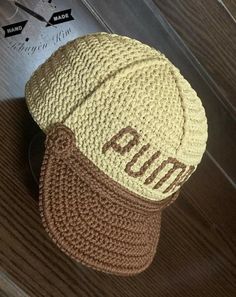 a crocheted hat with the word pum on it sitting on top of a wooden table