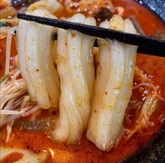 chopsticks sticking out of a bowl of soup with noodles and meat in it