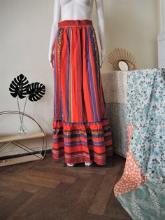 Beautiful True Vintage maxi skirt from the 1970s or early 1980s. Heavy cotton fabric, bold stripes with folk border embroidery. High waisted, two buttons and zipper. Two side pockets, ruffle hem. Unlined. Looks great with a simple white t-shirt, a pair of clogs and a tan 70s purse or wicker basket. BRAND: No brand label anymore ERA: 1970s, 1980s COLOR: Red, blue, green, purple, yellow, brown FABRIC: 100% cotton SIZE: No size tag, fits best a size S-M - please check measurements below for referen Red Bohemian Maxi Skirt, Red Folk Style Maxi Dress, Red Bohemian Cotton Skirt, Hippie Style Red Maxi Skirt For Festivals, Bohemian Red Cotton Skirt, Hippie Red Maxi Skirt For Festivals, Red Bohemian Maxi Skirt For Festival, Orange Cotton Bohemian Maxi Dress, Orange Bohemian Cotton Maxi Dress