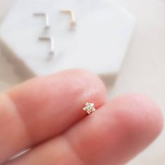 a person holding a tiny diamond ring in their left hand, with the cross on it