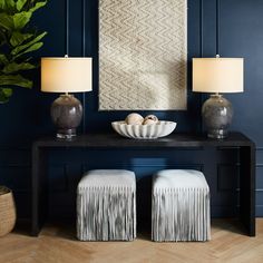 a table with two lamps on top of it next to some stools and a bowl