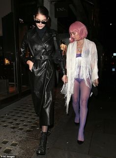 two women dressed in black and white are walking down the street with one holding her hand