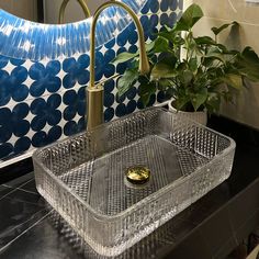 a glass sink with a gold faucet in the middle