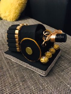 a black and gold decorated wine bottle sitting on top of a table next to a yellow pillow