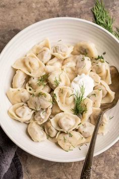 a white bowl filled with dumplings and sour cream